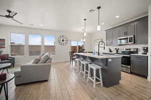 Kitchen featuring light wood finished floors, appliances with stainless steel finishes, open floor plan, and light countertops