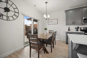 Dining room with light wood finished floors, visible vents, baseboards, and a chandelier