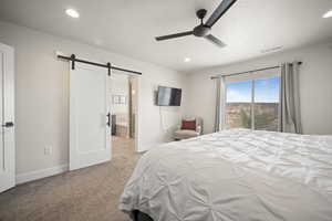 Bedroom with a barn door, carpet flooring, visible vents, and baseboards