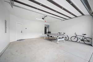 Garage with a garage door opener, gas water heater, and electric panel