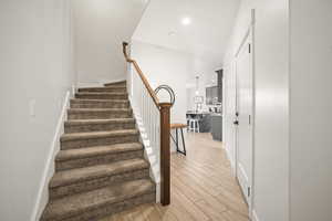 Staircase featuring wood finished floors and recessed lighting