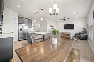 Dining space featuring ceiling fan with notable chandelier, wood tiled floor, visible vents, and recessed lighting