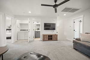 Carpeted living room featuring recessed lighting, visible vents, ceiling fan, and washing machine and clothes dryer