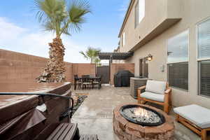 View of patio with outdoor dining area, a fenced backyard, a fire pit, a grill, and a pergola