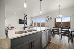 Kitchen with a sink, wood tiled floor, open floor plan, and dishwasher