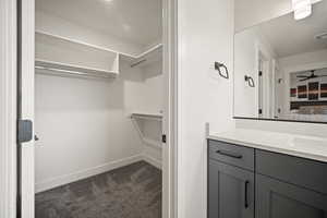 Bathroom with ensuite bath, a spacious closet, baseboards, and vanity