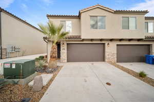 Mediterranean / spanish-style house with a garage, stone siding, concrete driveway, and stucco siding