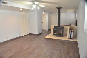 Living area with a wood stove, light wood-type flooring, visible vents, and baseboards