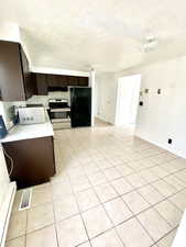 Kitchen with electric range, visible vents, freestanding refrigerator, light countertops, and dark brown cabinets