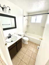 Bathroom with a textured ceiling, vanity, visible vents, shower / bathing tub combination, and tile patterned floors