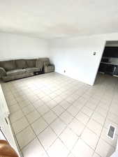 Unfurnished living room with visible vents, a textured ceiling, and light tile patterned floors