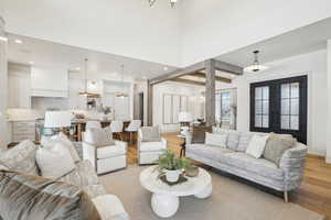 Living area featuring french doors, a notable chandelier, recessed lighting, light wood-style flooring, and baseboards