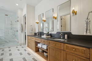 Bathroom featuring double vanity, a marble finish shower, a sink, and recessed lighting