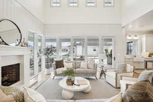 Living room featuring a fireplace with raised hearth, light wood-style flooring, and a high ceiling