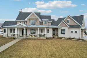 View of front of property featuring a standing seam roof, a shingled roof, a porch, and board and batten siding