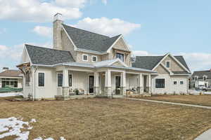 View of front of home with a porch, board and batten siding, a shingled roof, and a front yard