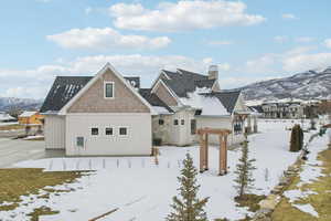 Snow covered back of property featuring a chimney and a mountain view