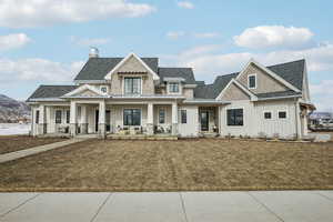 View of front of house with metal roof, covered porch, a shingled roof, board and batten siding, and a standing seam roof