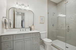 Full bathroom featuring toilet, a shower stall, and vanity