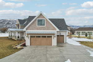 View of front of property with covered porch, board and batten siding, a standing seam roof, a mountain view, and driveway