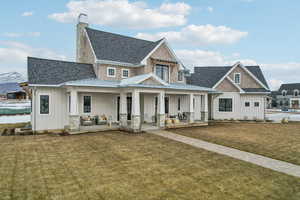 View of front of house with board and batten siding, covered porch, roof with shingles, and a front lawn