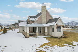 Snow covered back of property featuring roof with shingles, board and batten siding, a standing seam roof, a mountain view, and metal roof