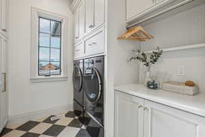 Laundry area featuring dark floors, visible vents, baseboards, washer and dryer, and cabinet space