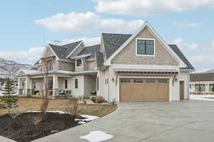 Shingle-style home with an attached garage, a standing seam roof, driveway, and board and batten siding