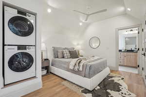 Bedroom featuring lofted ceiling, stacked washer and dryer, ceiling fan, and light wood-style floors