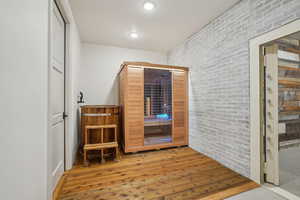 Interior space with recessed lighting, brick wall, and wood finished floors