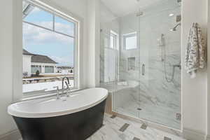 Bathroom with a freestanding bath, marble finish floor, and a marble finish shower