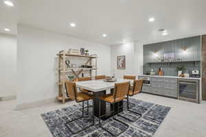 Dining room featuring light carpet, beverage cooler, visible vents, a bar, and recessed lighting