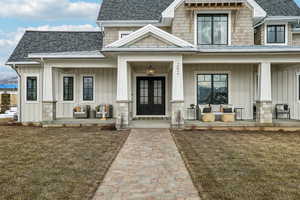 View of exterior entry with a shingled roof, a porch, and board and batten siding