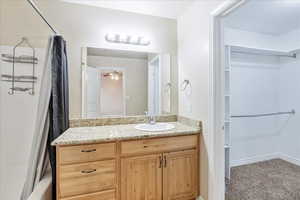 Full bathroom featuring a walk in closet, shower / tub combo with curtain, and vanity