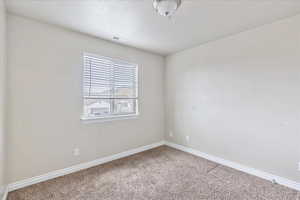 Unfurnished room with a textured ceiling, carpet flooring, visible vents, and baseboards