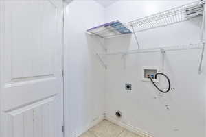 Laundry area featuring hookup for a washing machine, light tile patterned flooring, electric dryer hookup, and baseboards