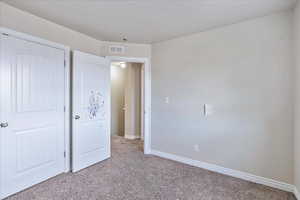 Unfurnished bedroom featuring light carpet, visible vents, and baseboards