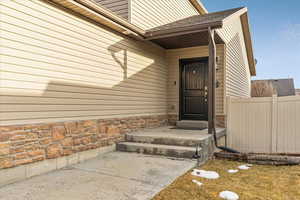 Entrance to property featuring stone siding and fence