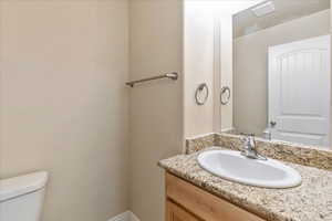 Bathroom with toilet, visible vents, and vanity