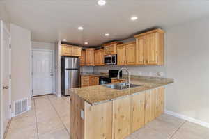 Kitchen with stainless steel appliances, visible vents, a sink, and light brown cabinets