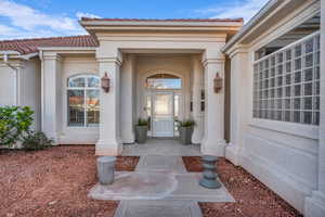 View of exterior entry with a tiled roof and stucco siding