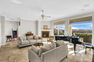 Living room featuring a tiled fireplace, baseboards, and crown molding