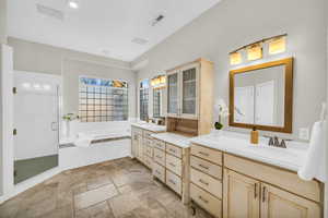 Full bath featuring visible vents, stone tile flooring, vanity, a shower stall, and a bath