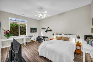 Bedroom with a ceiling fan, wood finished floors, visible vents, and baseboards