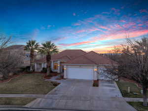 Mediterranean / spanish house featuring a garage, a tiled roof, driveway, a lawn, and stucco siding