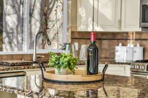 Details featuring appliances with stainless steel finishes, dark stone counters, white cabinetry, and tasteful backsplash