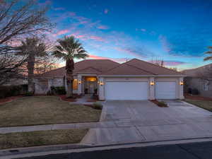 Mediterranean / spanish-style home featuring a garage, a tile roof, driveway, stucco siding, and a front lawn