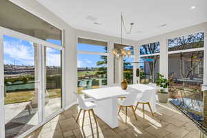 Sunroom / solarium featuring visible vents, a notable chandelier, and a water view