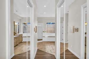 Full bathroom featuring a garden tub, stone tile floors, vanity, baseboards, and a stall shower