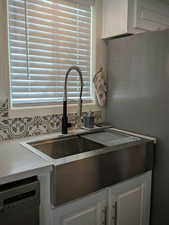 Interior details featuring dishwasher, light countertops, freestanding refrigerator, and white cabinetry